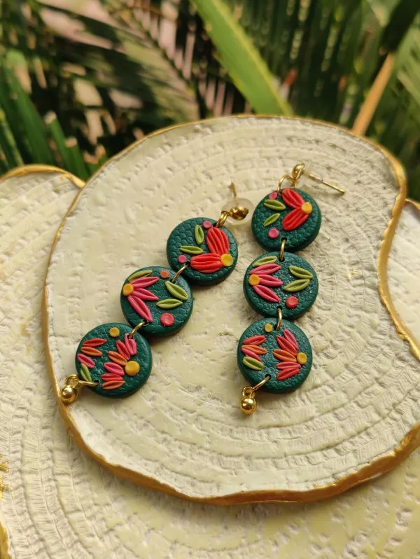 Round earrings design is a fun way to add color to your look. 3 small rounds with a dark green base, embellished with multi-colored intricate style to work its magic on you.