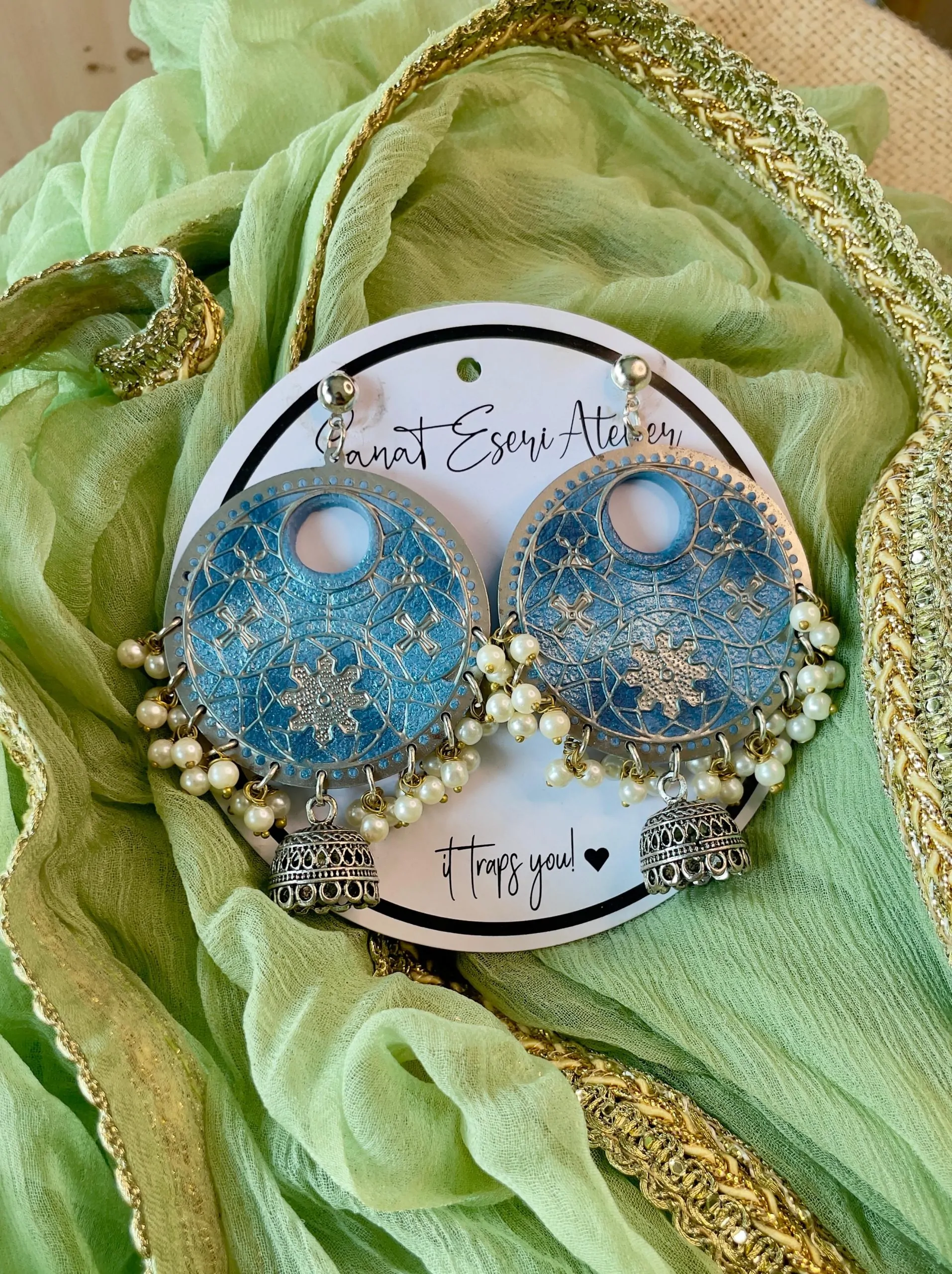 These big round zinc earrings are perfect for any occasion! They have a beautiful handmade design with small pearls and antique silver jhumkas hanging at the bottom. The unique pattern gives them a stylish and traditional look, making them great for weddings, festivals, and parties.