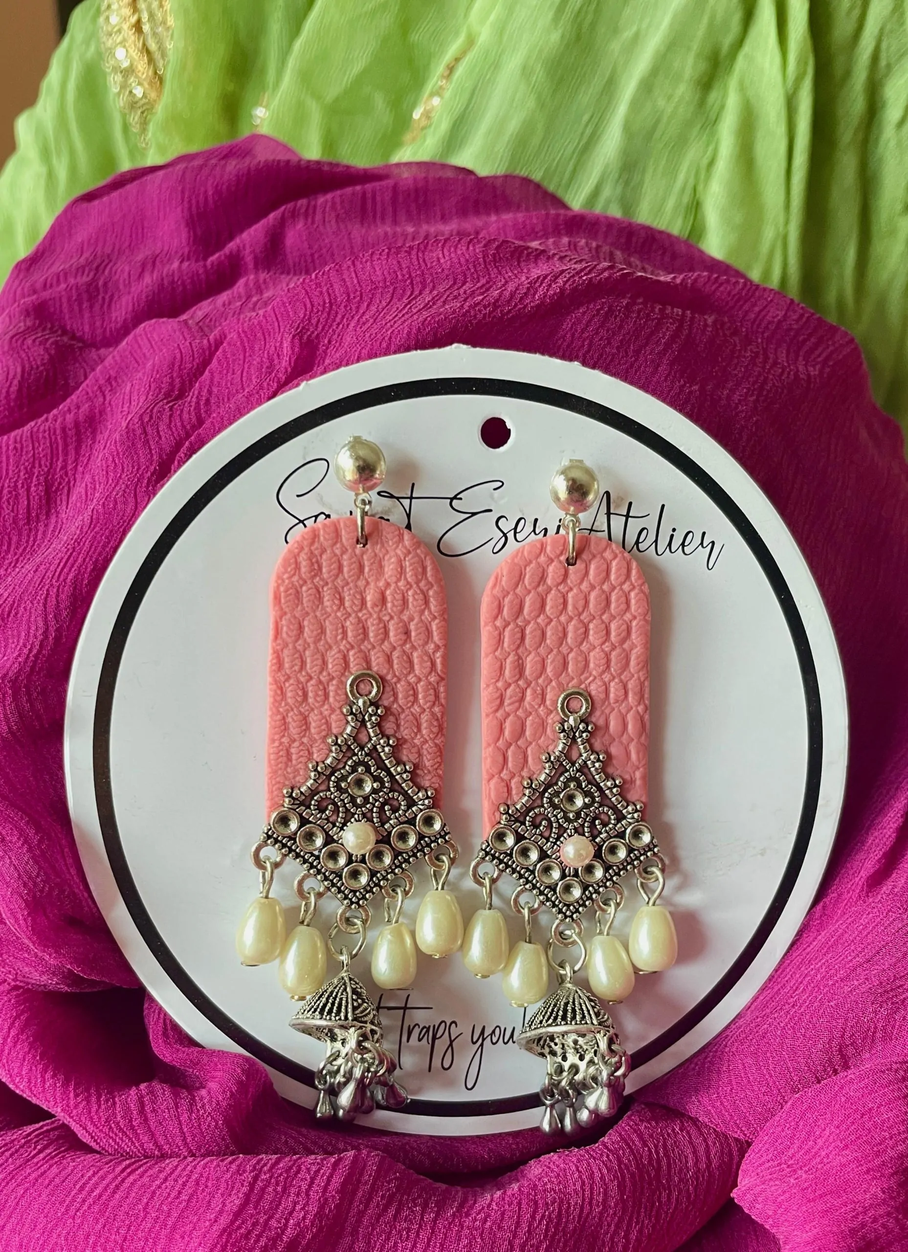 The highlight of this design is the intricate antique silver charm, shaped like a diamond with fine detailing and a central pearl. Below the charm, dangling pearl-like beads add a touch of grace and movement, along with small jhumka-style metallic bells.