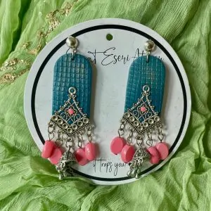 The highlight of this design is the intricate antique silver charm, shaped like a diamond with fine detailing and a central pearl. Below the charm, dangling pearl-like beads add a touch of grace and movement, along with small jhumka-style metallic bells.