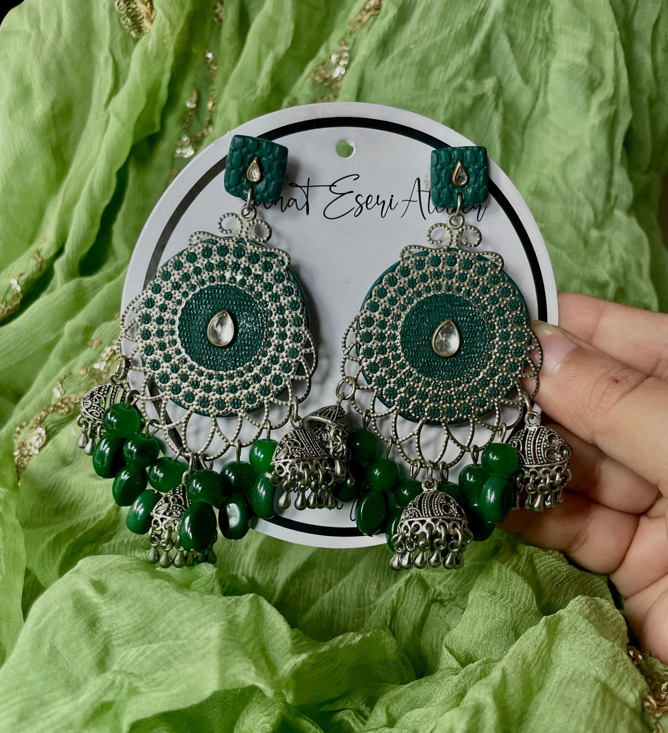 These are our green Chandbali earrings. Designed with intricate silver work, small jhumkas, and green beads, these earrings are perfect for weddings, parties, and festive occasions. The lightweight yet statement design makes them comfortable to wear all day. Pair them with ethnic outfits like sarees, lehengas, or kurtis for a complete look.