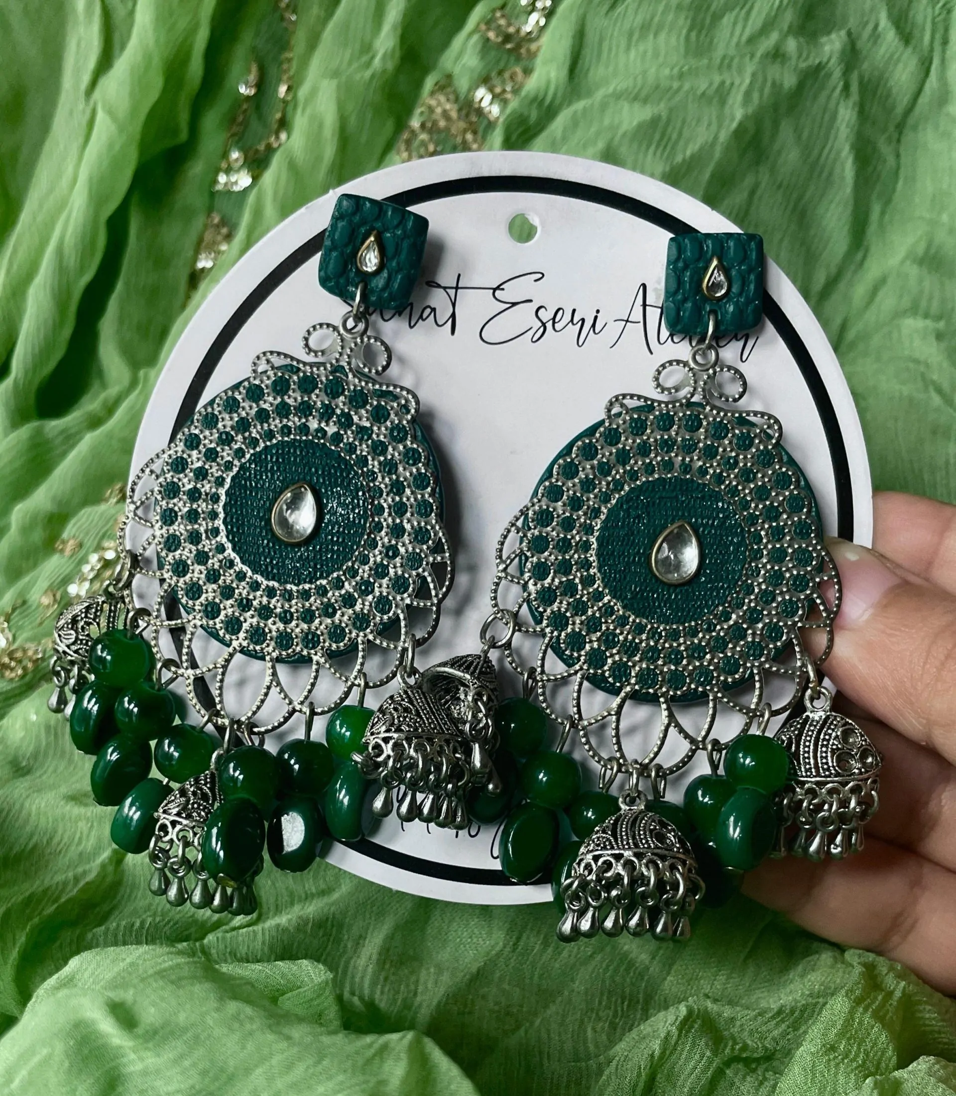 These are our green Chandbali earrings. Designed with intricate silver work, small jhumkas, and green beads, these earrings are perfect for weddings, parties, and festive occasions. The lightweight yet statement design makes them comfortable to wear all day. Pair them with ethnic outfits like sarees, lehengas, or kurtis for a complete look.