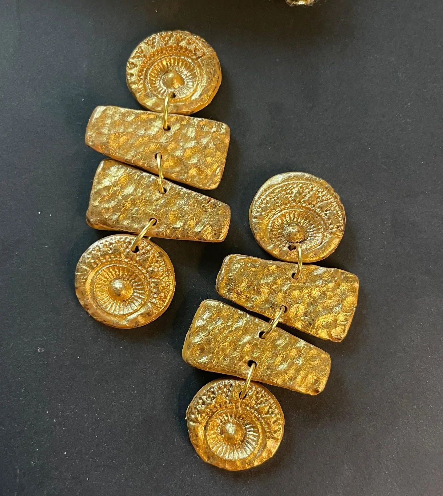 Long, gold-toned dangle earrings with hammered and circular shapes. Handmade from polymer clay, giving a lightweight yet bold statement look.