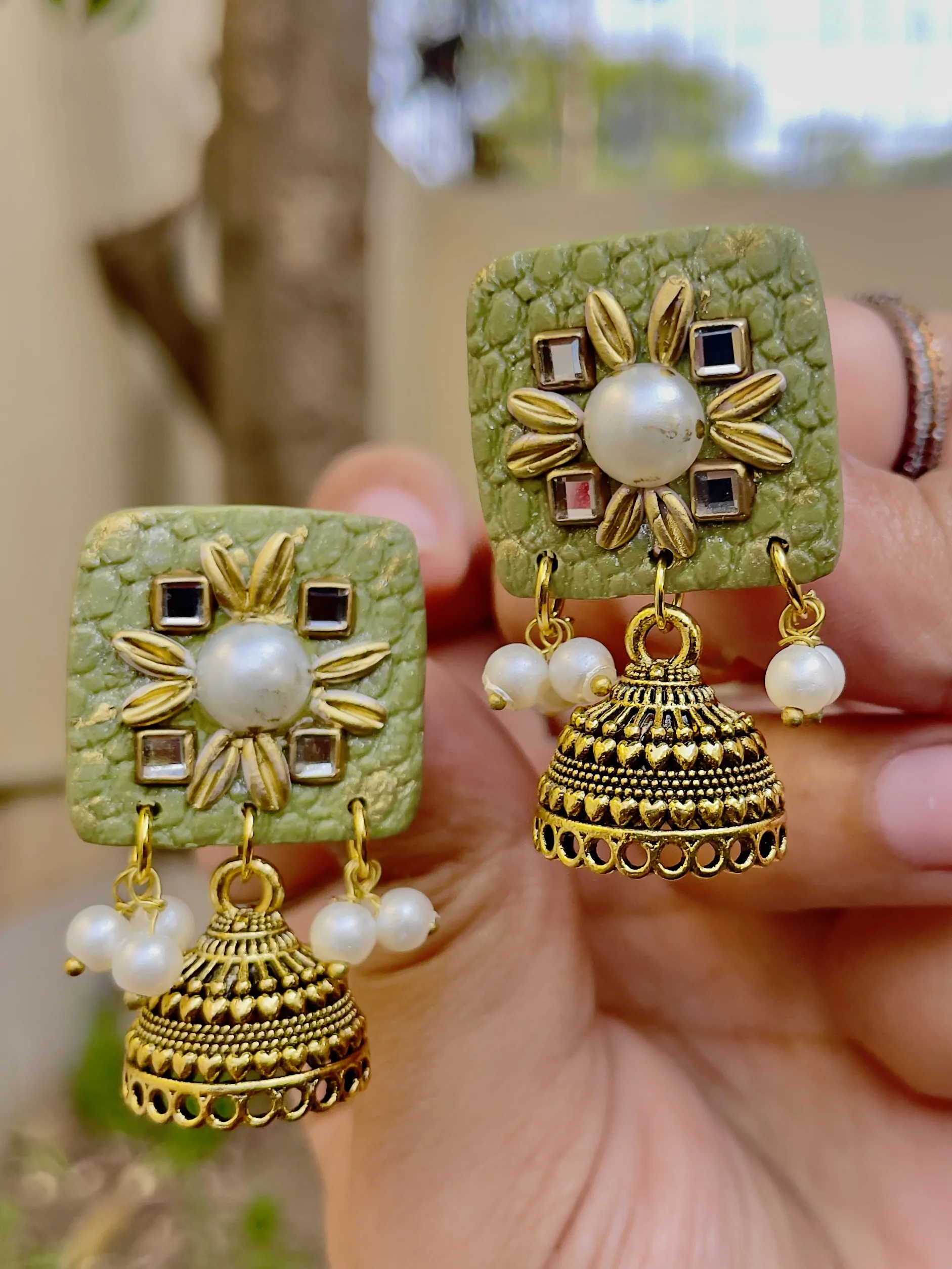 Olive green square textured earrings with gold Jhumka bells and white pearls.