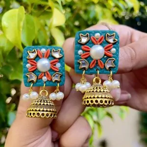 Teal square textured earrings with coral floral accents, gold Jhumka bells, and white pearls.