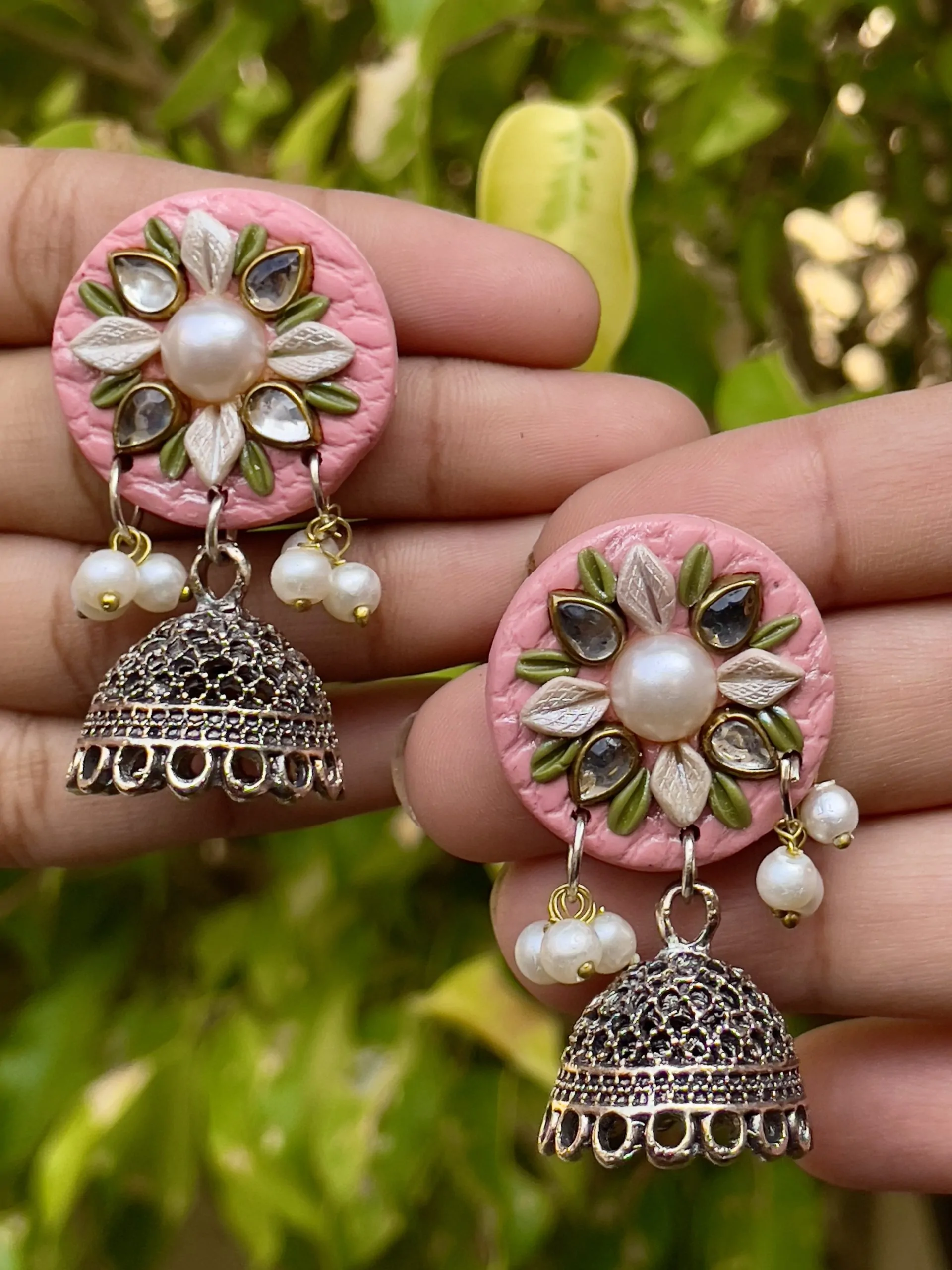Pink round textured earrings with gold Jhumka bells.