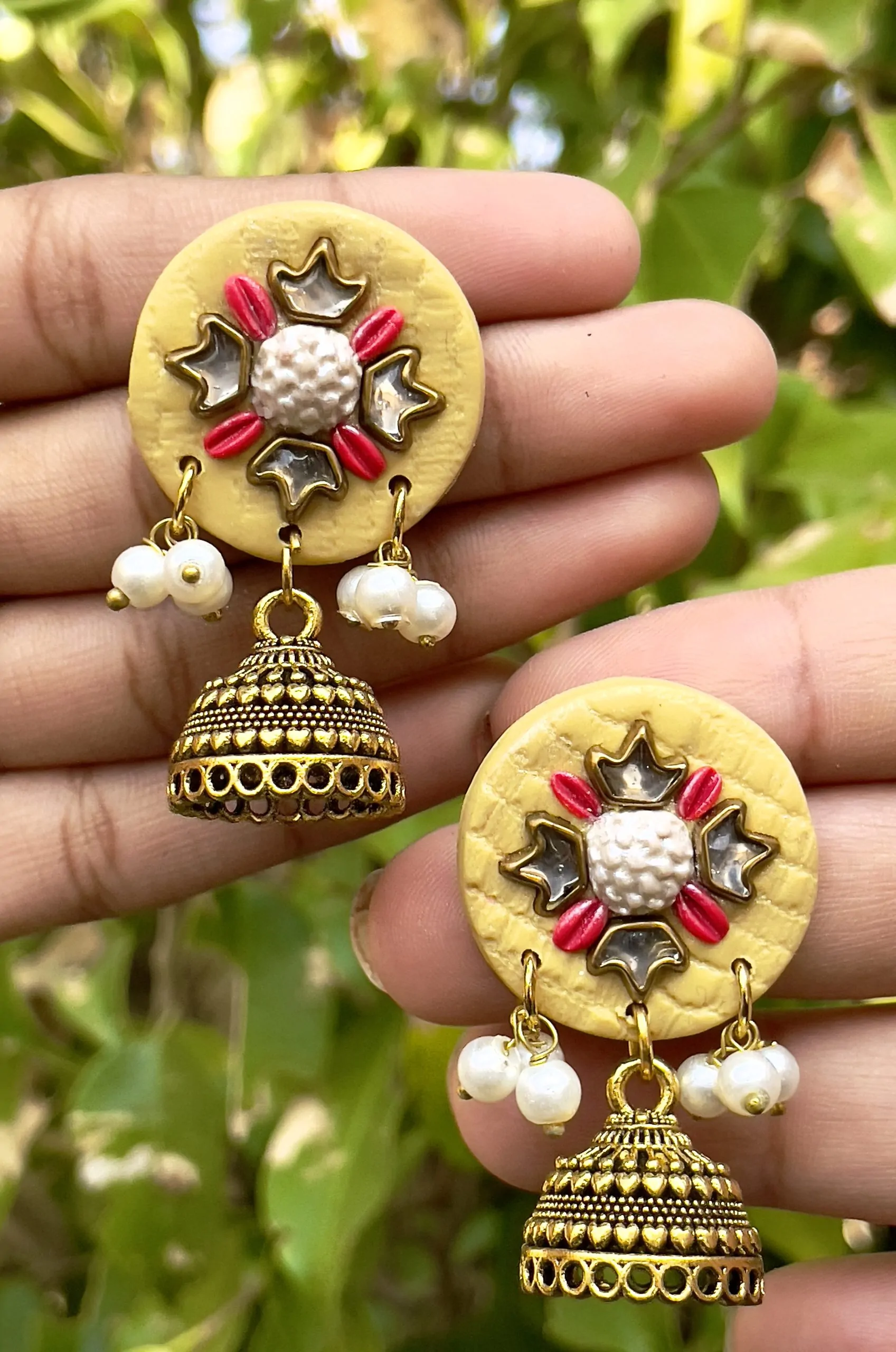 Butter yellow round textured earrings with gold Jhumka bells.