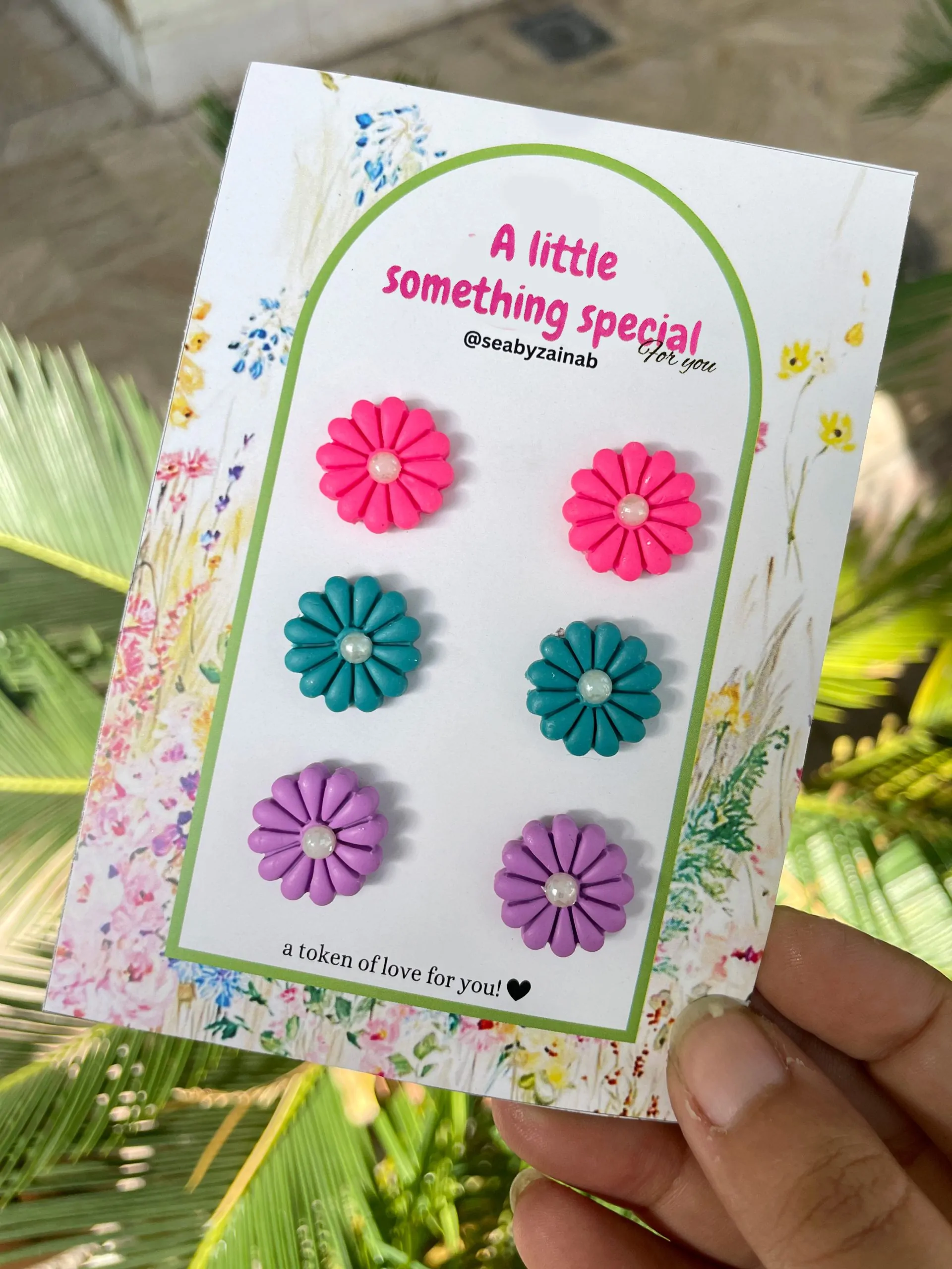 Three pairs of flower stud earrings in purple, pink, and ferozi