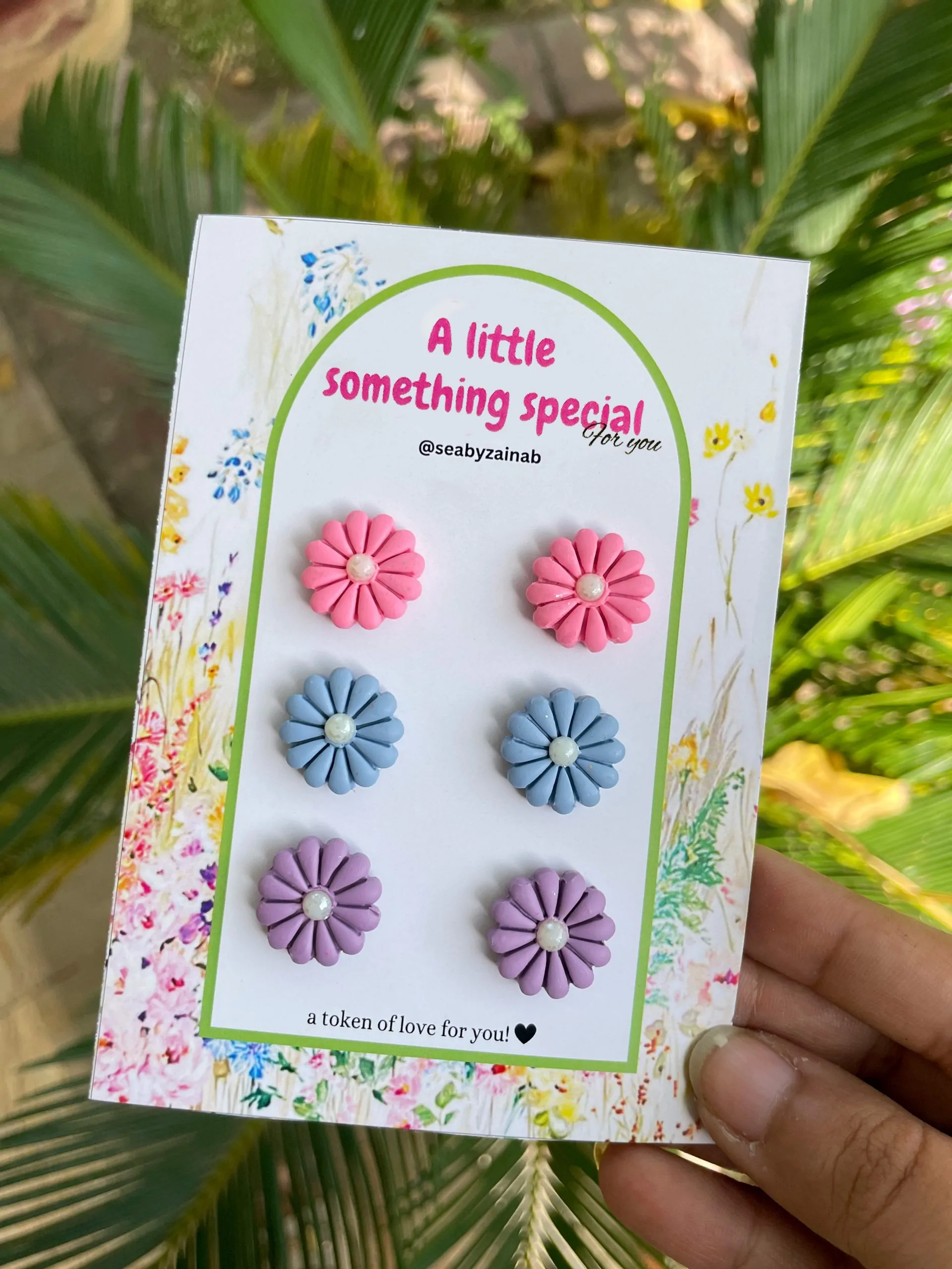 Pastel pink, blue, and purple flower earrings on a floral gift card.