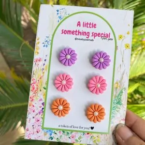 Three pairs of flower stud earrings in purple, pink, and orange.