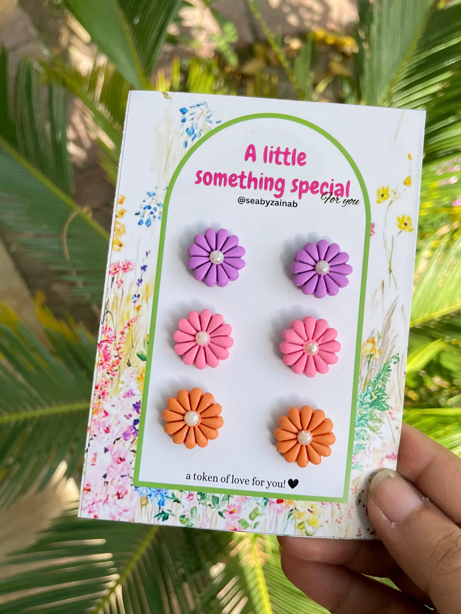 Three pairs of flower stud earrings in purple, pink, and orange.