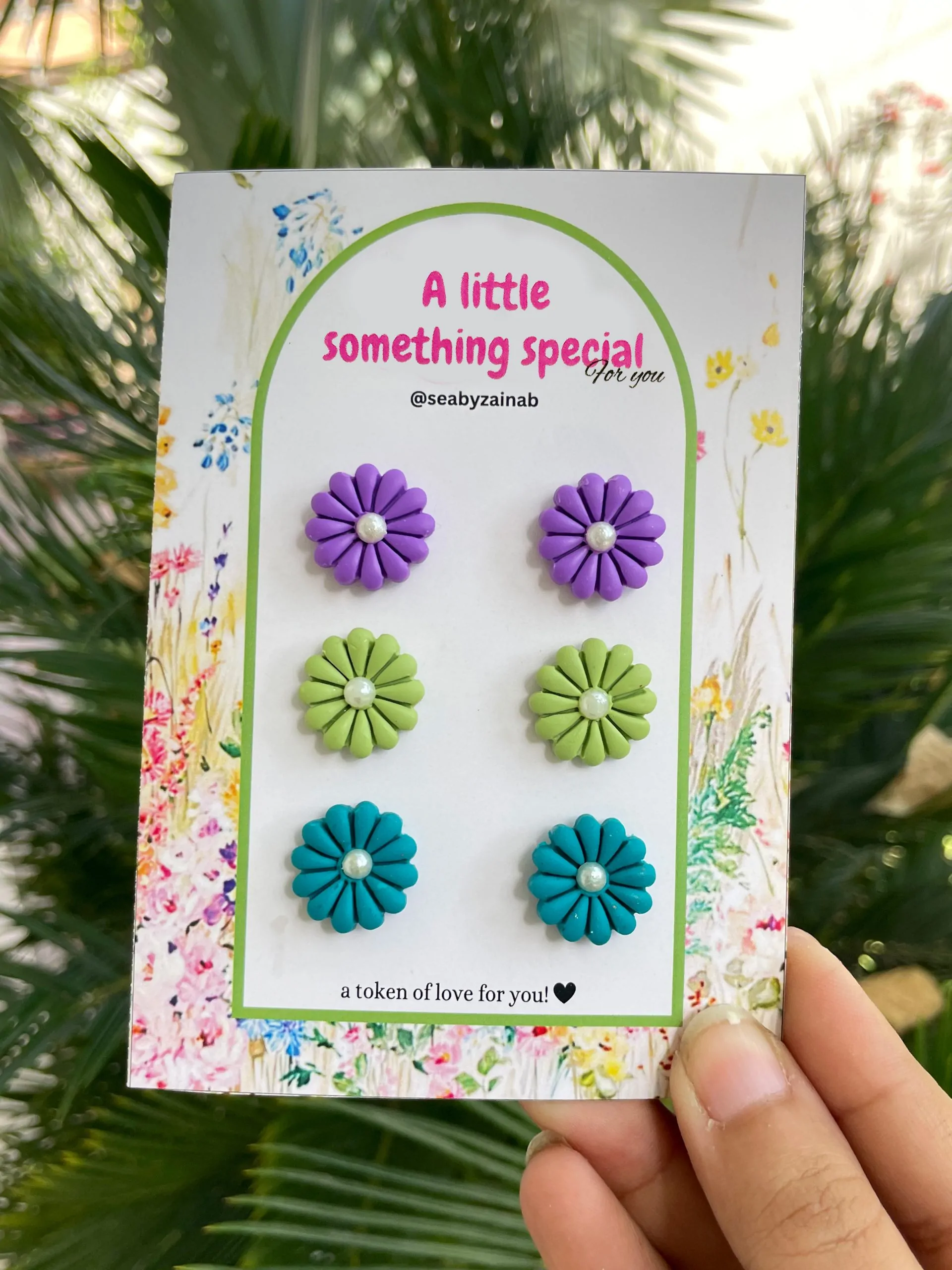 Three pairs of flower stud earrings in purple, green, ferozi