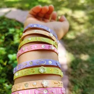 Artisan stack of pastel lilac, mint, and pink textured bangles with hand-sculpted white clay flowers, gold embroidery, and pearl accents