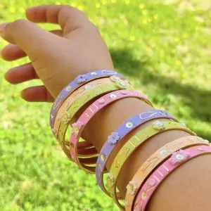 Artisan stack of pastel lilac, mint, and pink textured bangles with hand-sculpted white clay flowers, gold embroidery, and pearl accents