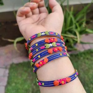 Artisan stack of royal blue textured bangles featuring hand-sculpted pink and orange clay flowers with silver metallic threading.