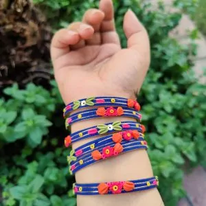 Artisan stack of royal blue textured bangles featuring hand-sculpted pink and orange clay flowers with silver metallic threading.