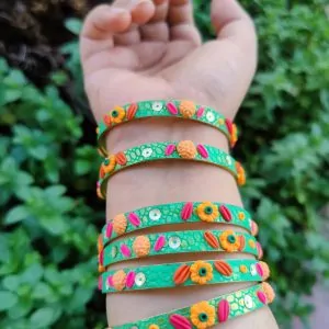 Artisan stack of emerald green textured bangles featuring hand-sculpted orange and pink clay flowers with silver sequin accents.