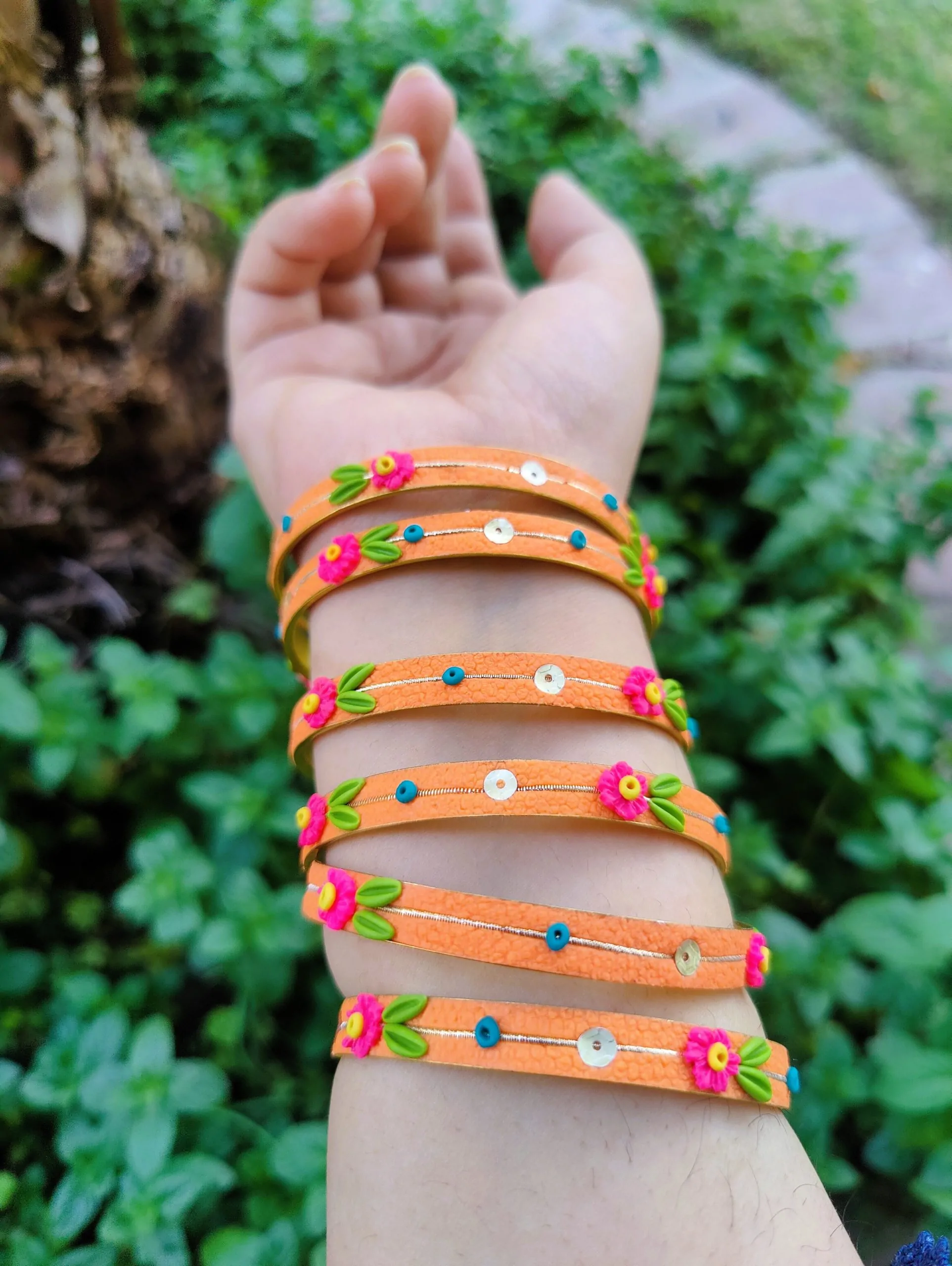 Handcrafted zesty orange textured bangles with 3D neon pink clay flowers and gold sequin details