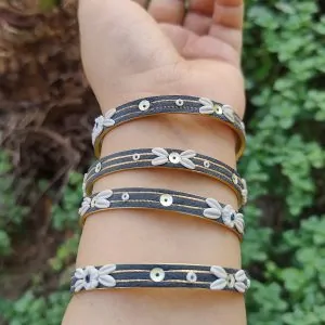 Artisan stack of charcoal grey textured bangles featuring hand-sculpted white clay flowers, silver sequins, and gold metallic threading.