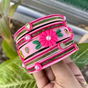 Artisan stack of fuchsia pink textured bangles featuring a large 3D clay flower, green metallic embroidery, and kundan crystal accents.