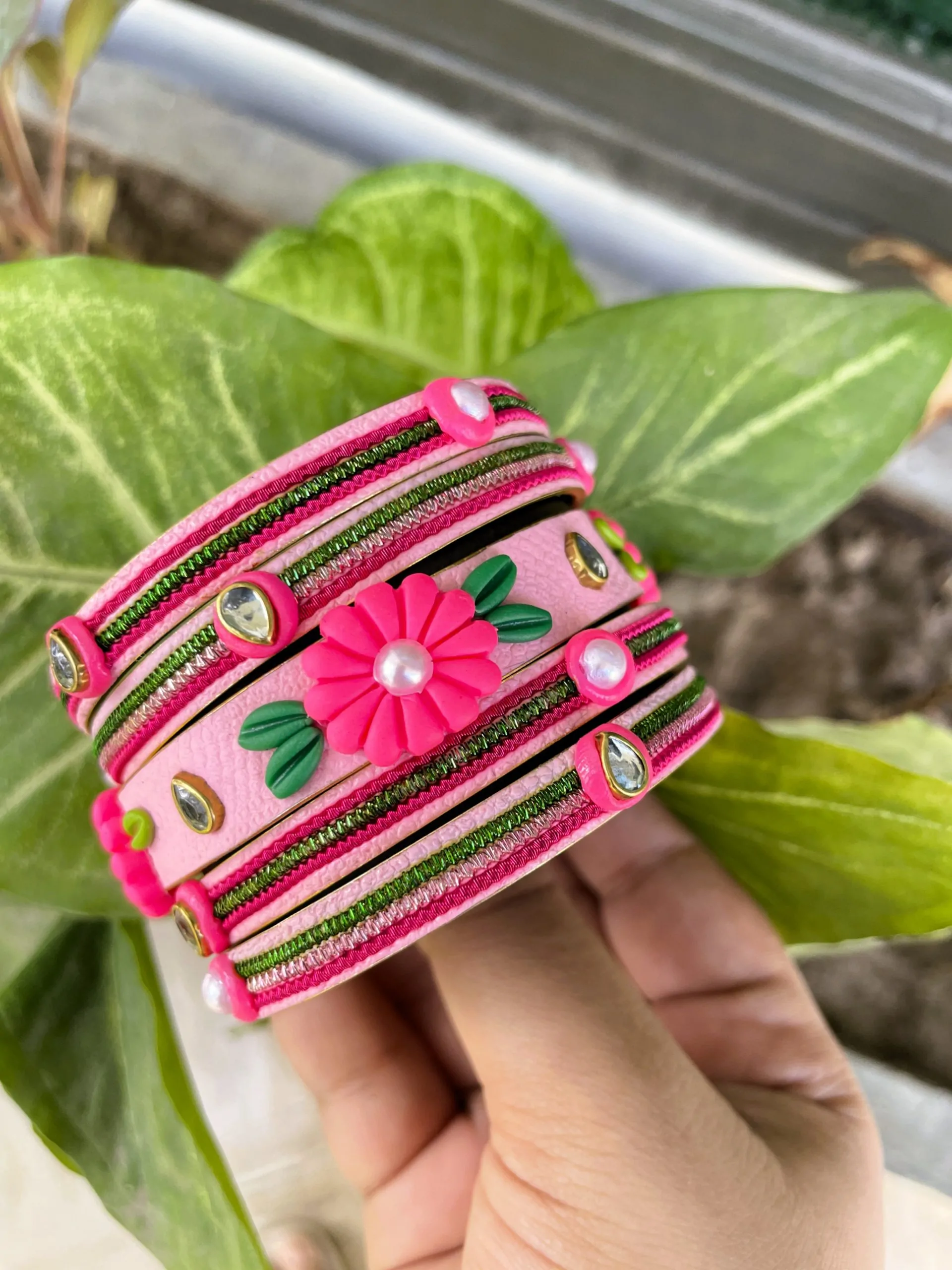 IMG_5078 Artisan stack of fuchsia pink textured bangles featuring a large 3D clay flower, green metallic embroidery, and kundan crystal accents.