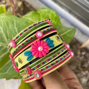 Artisan stack of lemon yellow textured bangles featuring a large 3D fuchsia clay flower, rainbow metallic embroidery, and crystal accents.