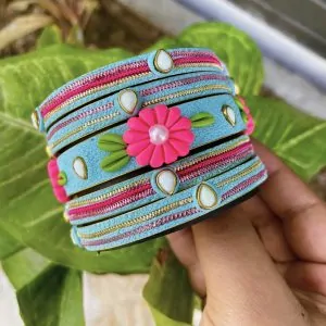 Artisan stack of sky blue textured bangles featuring a large 3D fuchsia clay flower, kundan stone accents, and pink metallic embroidery