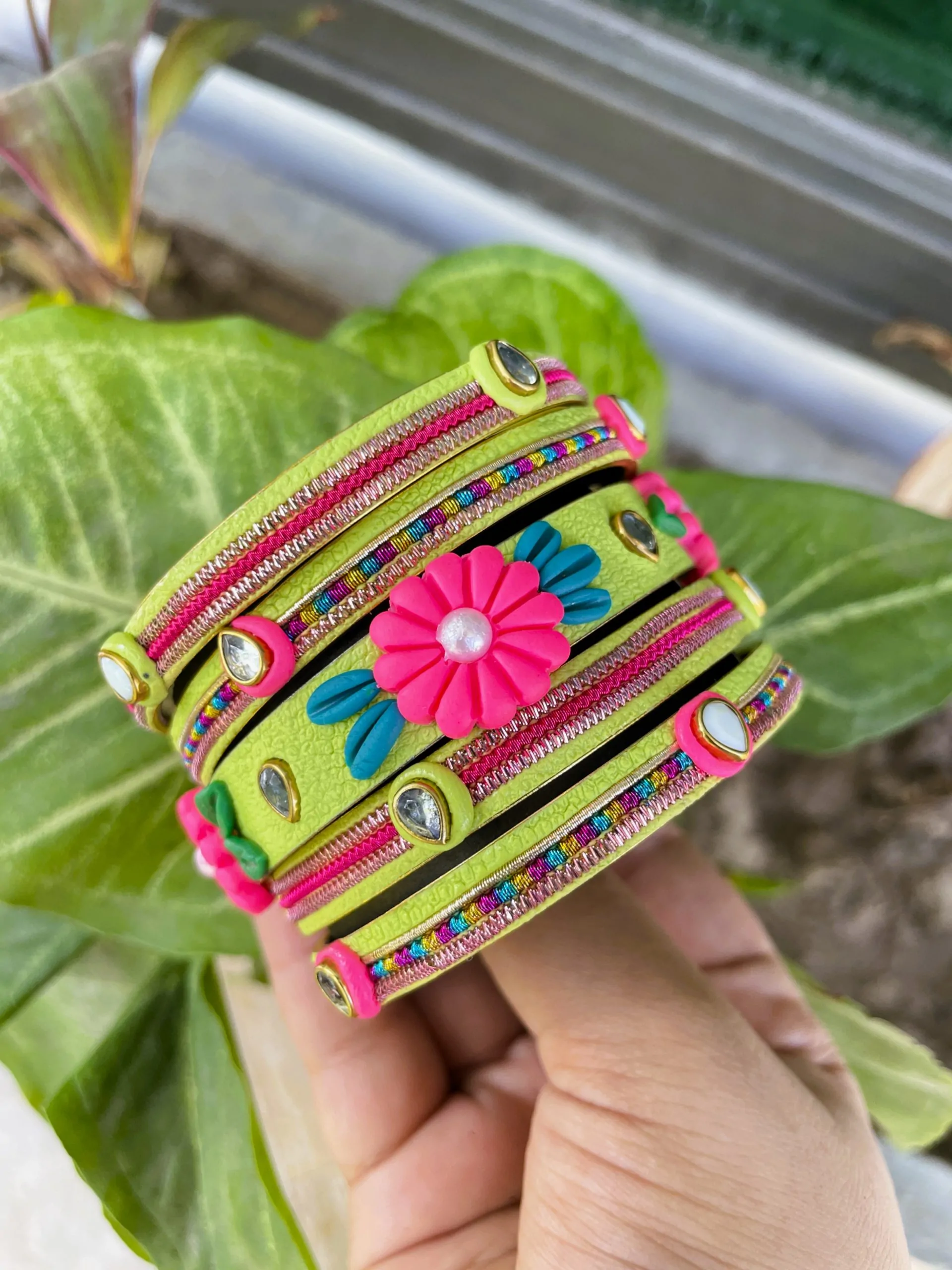 IMG_5091 Artisan stack of neon lime green textured bangles featuring a large 3D fuchsia clay flower, rainbow metallic embroidery, and crystal accents.
