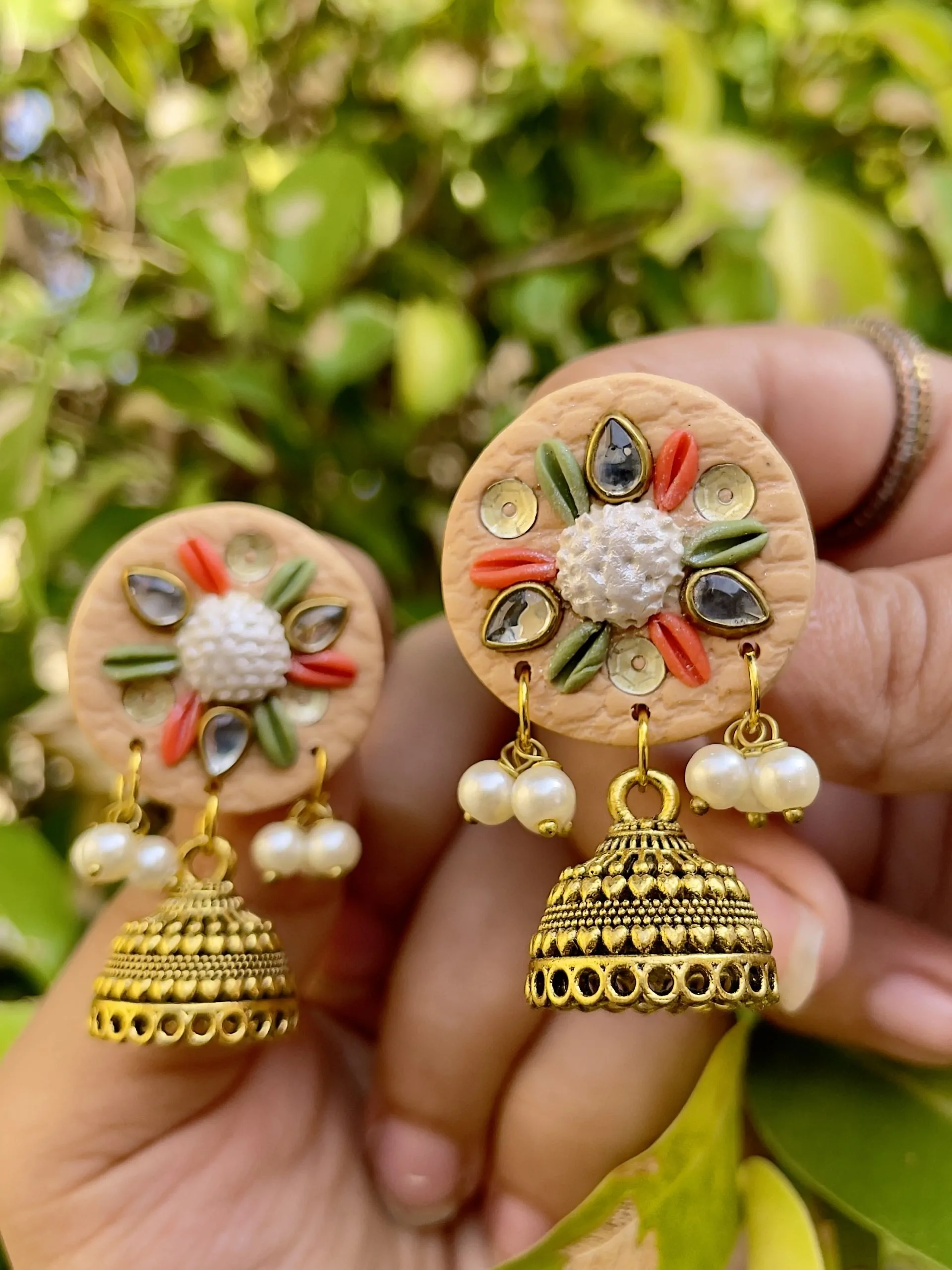 Peach round textured earrings with gold Jhumka bells and star mirrors.