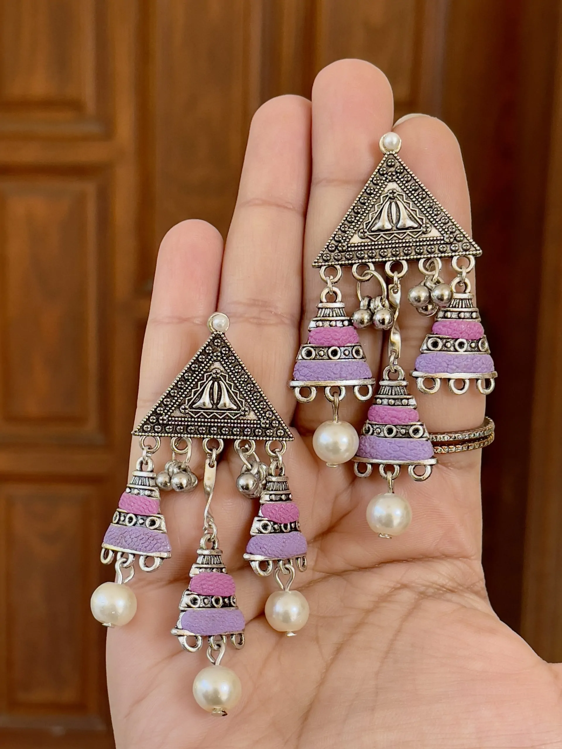 Tribal-style silver triangle chandelier earrings with magenta and lavender purple textured bead tassels and white pearl accents.