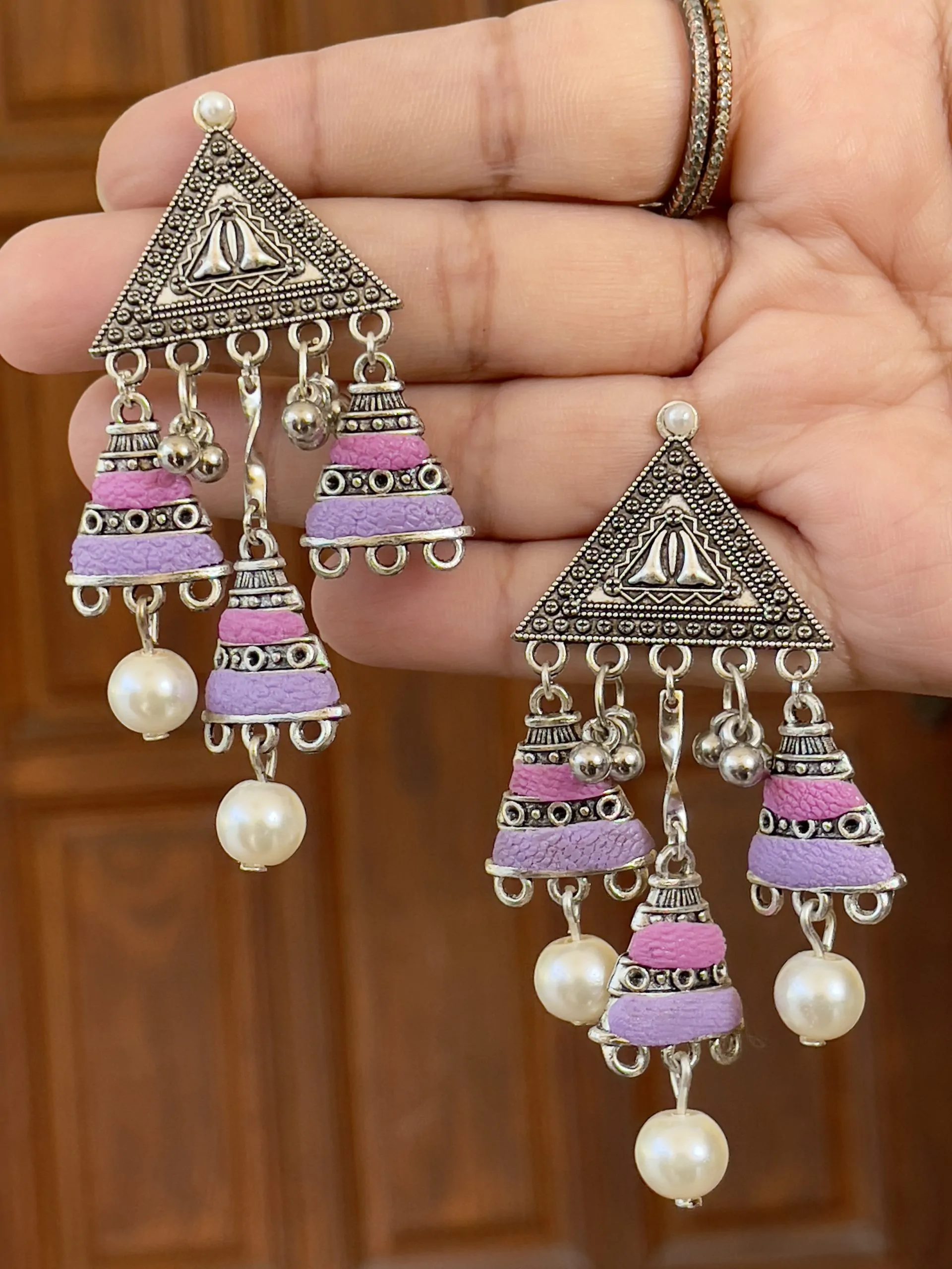 Tribal-style silver triangle chandelier earrings with magenta and lavender purple textured bead tassels and white pearl accents.