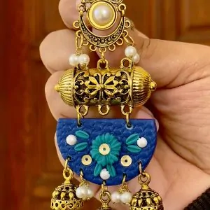 Close-up of textured blue half-moon earrings with teal flowers and gold-toned traditional dangles.
