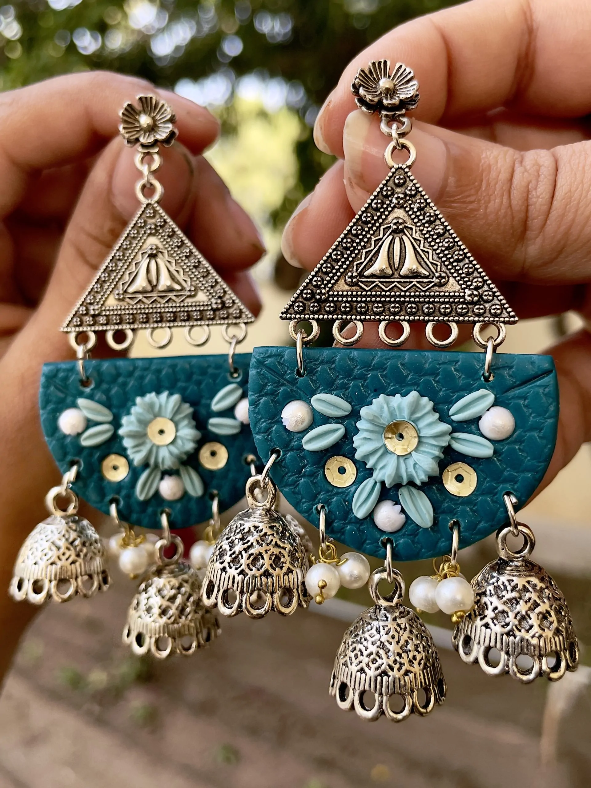 Teal half-moon chandelier earrings with silver filigree and five Jhumka bell drops